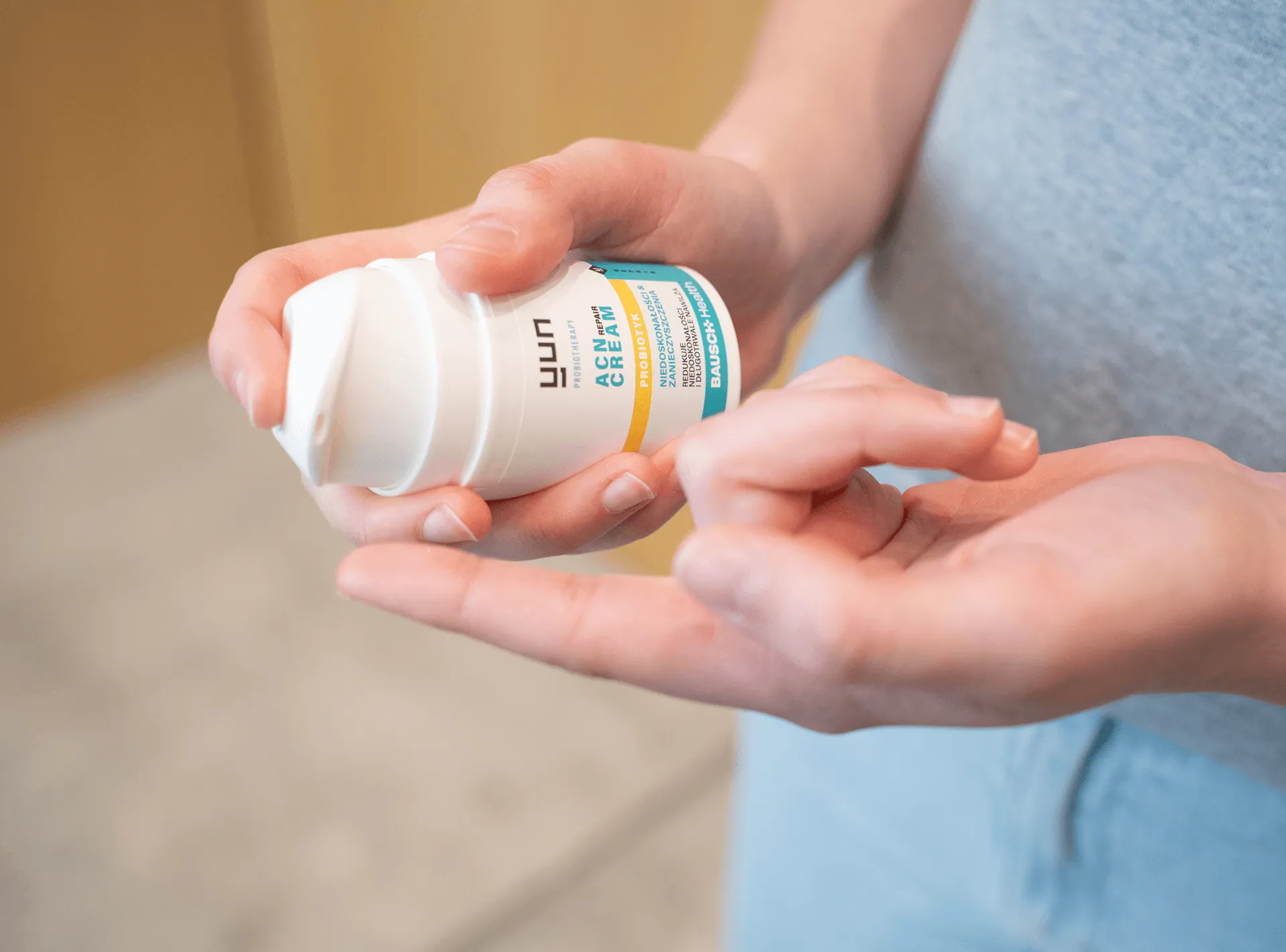 Osoba trzymająca i nakładająca na palec krem Yun ACN Repair Cream