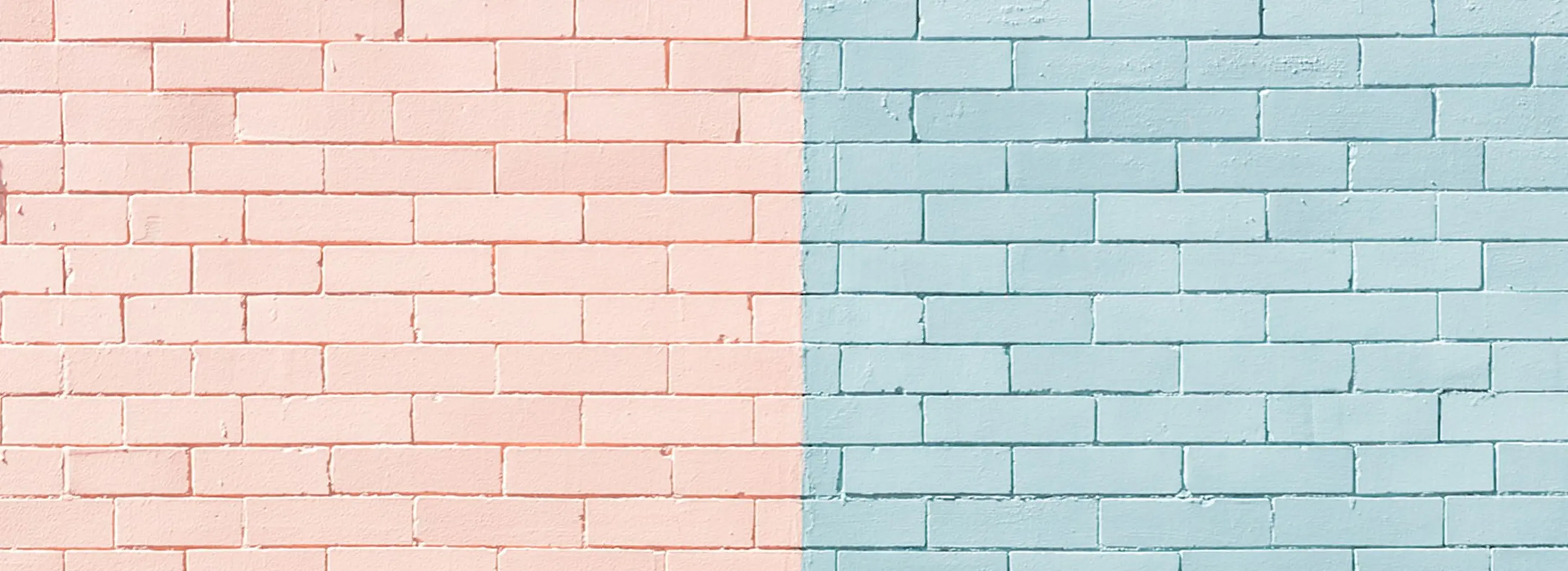 Ściana z cegieł pomalowana w dw&oacute;ch kolorach &ndash; pastelowy r&oacute;ż po lewej i jasny błękit po prawej stronie