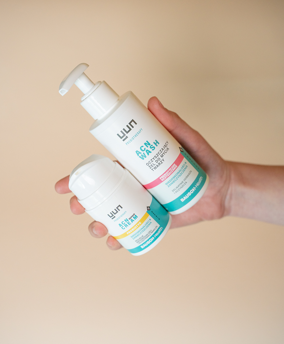 Produkty Yun ACN Wash i ACN Repair Cream trzymane w dłoni.
